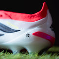 White soccer cleat with red accents on grass
