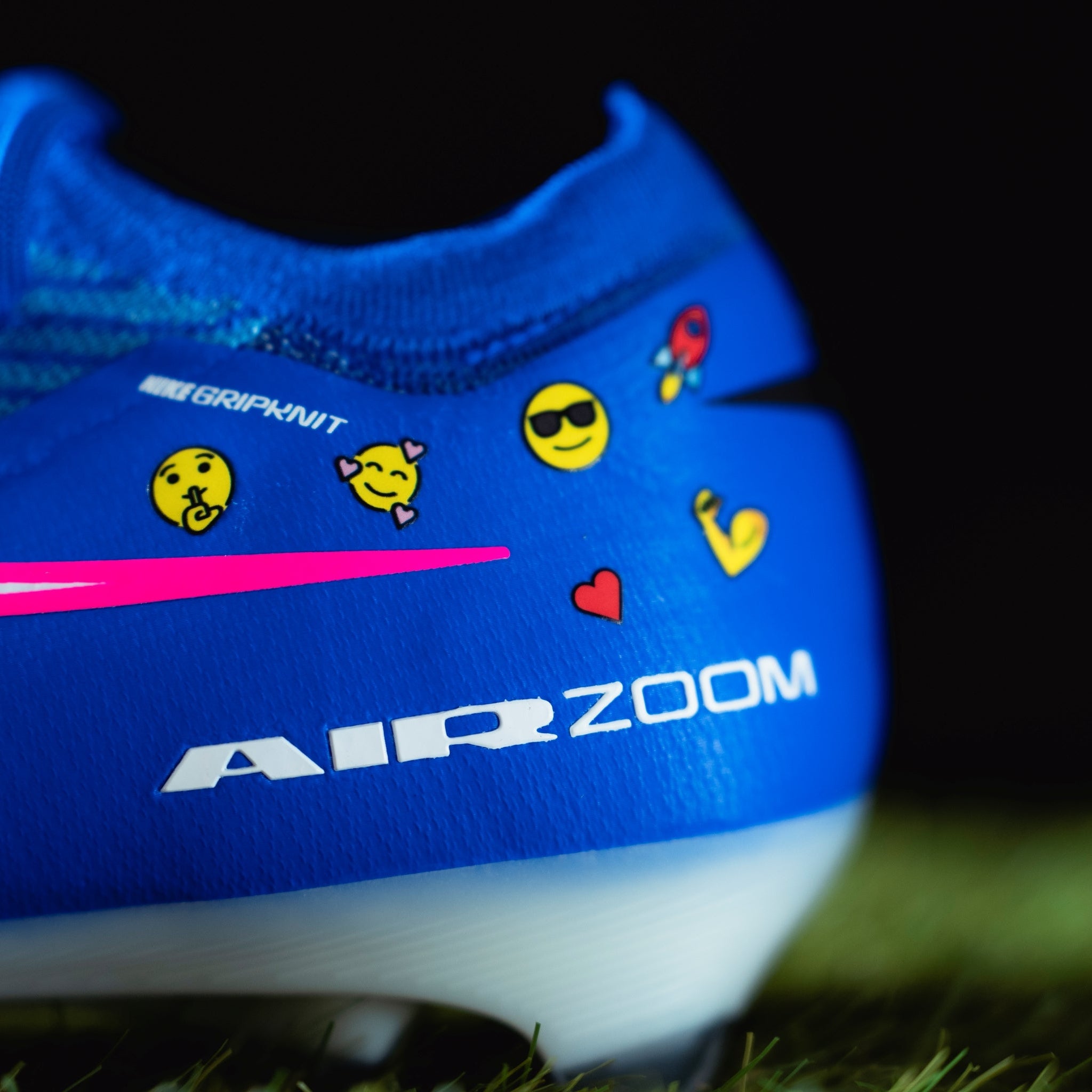 Blue sports shoe with colorful stickers on a grassy field