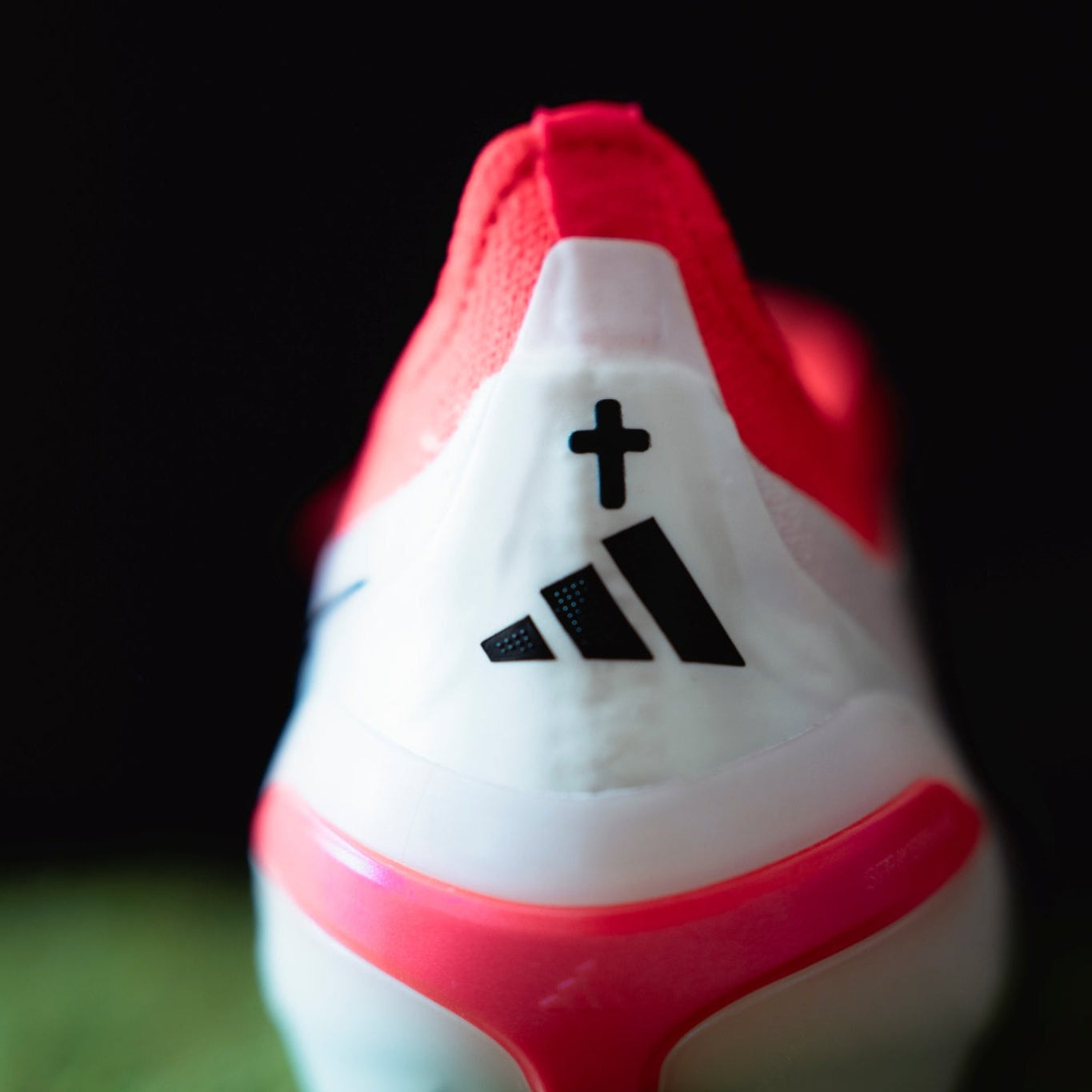 Close-up of a red and white sports shoe with Adidas logo on a dark background
